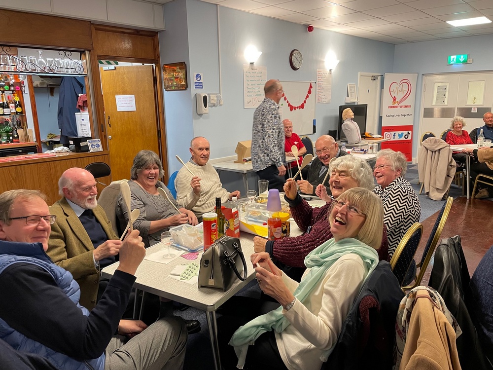 Picture of people having fun, one table waving wooden spoons as they came last in the quiz night