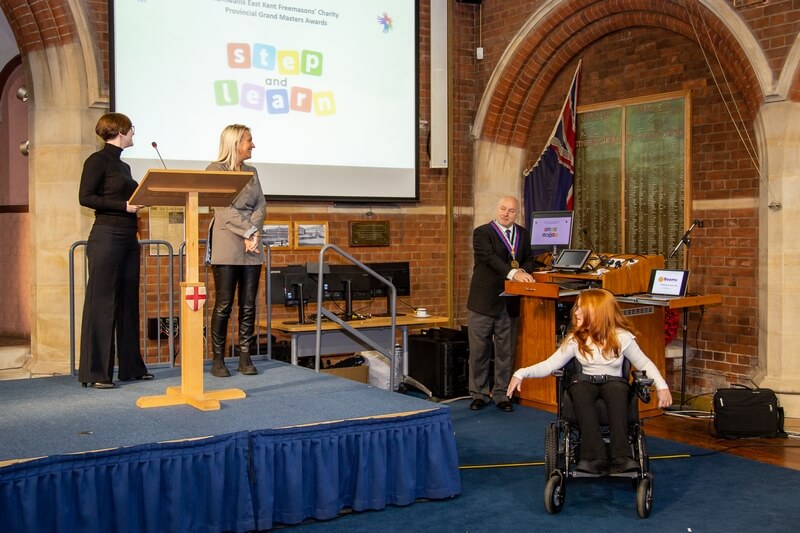Next picture is of the representatives of Step and Learn, with two of the ladies on the stage, and a young girl in a wheelchair just below