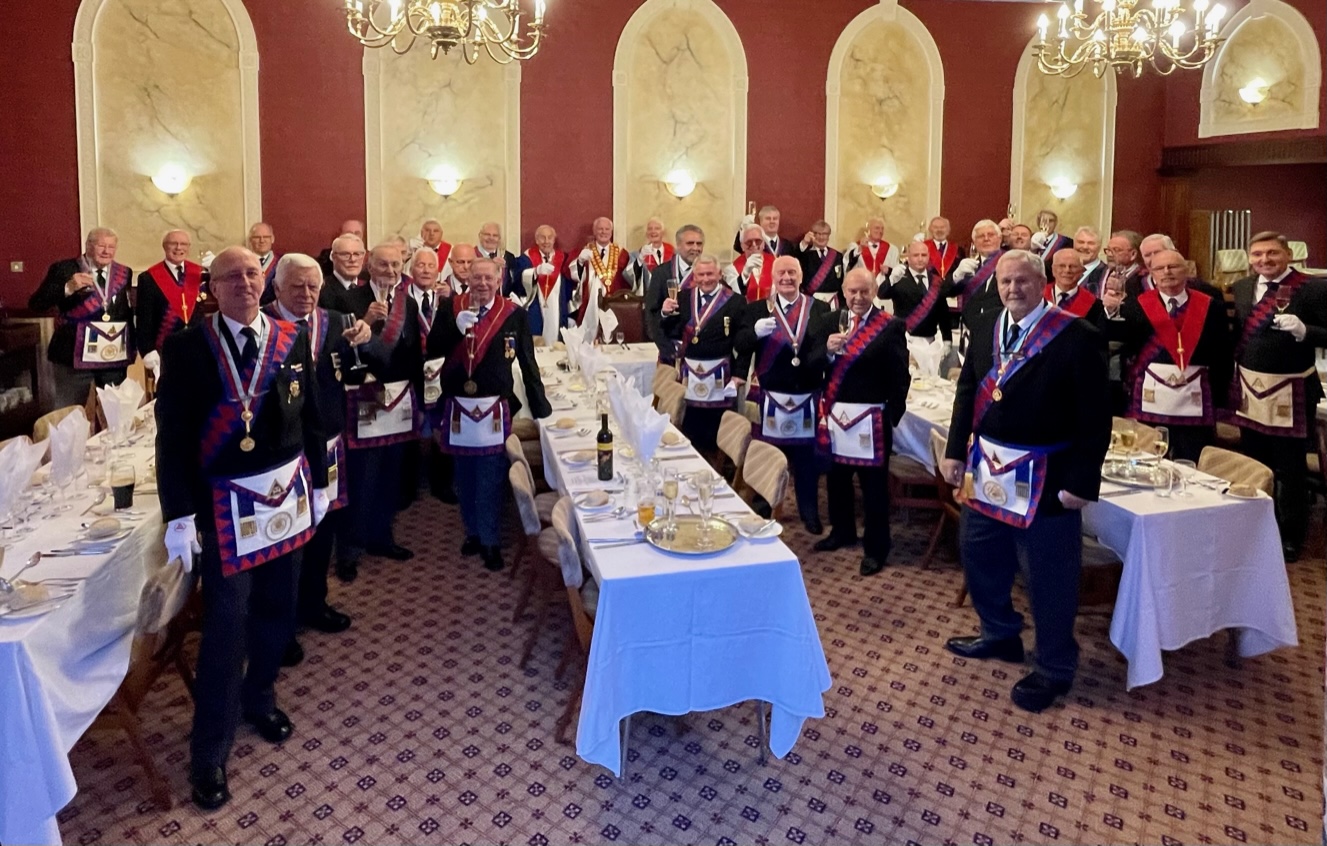 Picture showing members of the Chapter at the festive board, standing raising a glass to the 75 years of the chapter