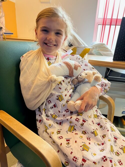 Ruby sitting up in the hospital bed, smiling with Mason by her side. 