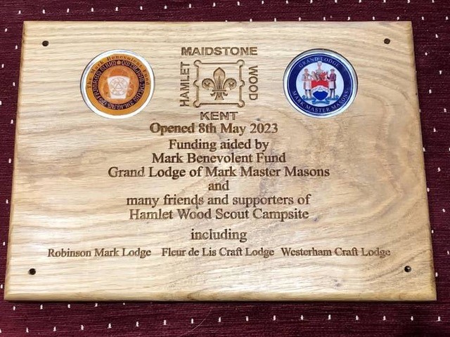 A picture of the official Wooden  Plaque showing the crest of Mark Masons,  the crest of the Grand Lodge of Mark Masons, the opening date 8th May 2023 along with the contributing lodges, Robinson Lodge, Fleur de Lis Lodge and Westerham Lodge. 