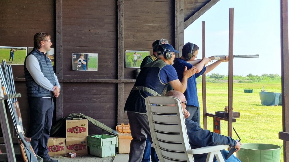 picture of a young shooter taking aim with the help of one of the shooting team