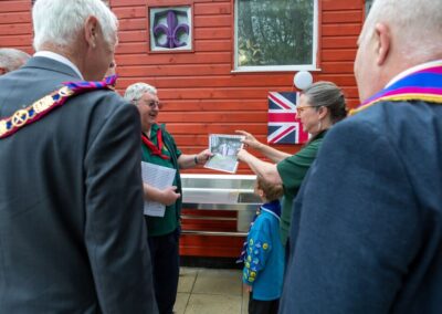 Two of the senior Scout leaders, holding a picture of the old toilet block, showing how it was, with members of the Freemasons looking on