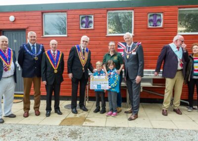 Picture of the Freemasons lined up, with the two young scouts holding the donation plaque