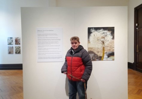 Gill at the exhibition standing in front of a photo